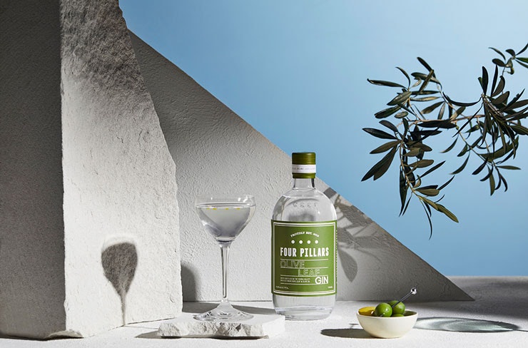 A stylised photo of Four Pillars Olive Leaf gin, featuring a martini and a bowl of olives.